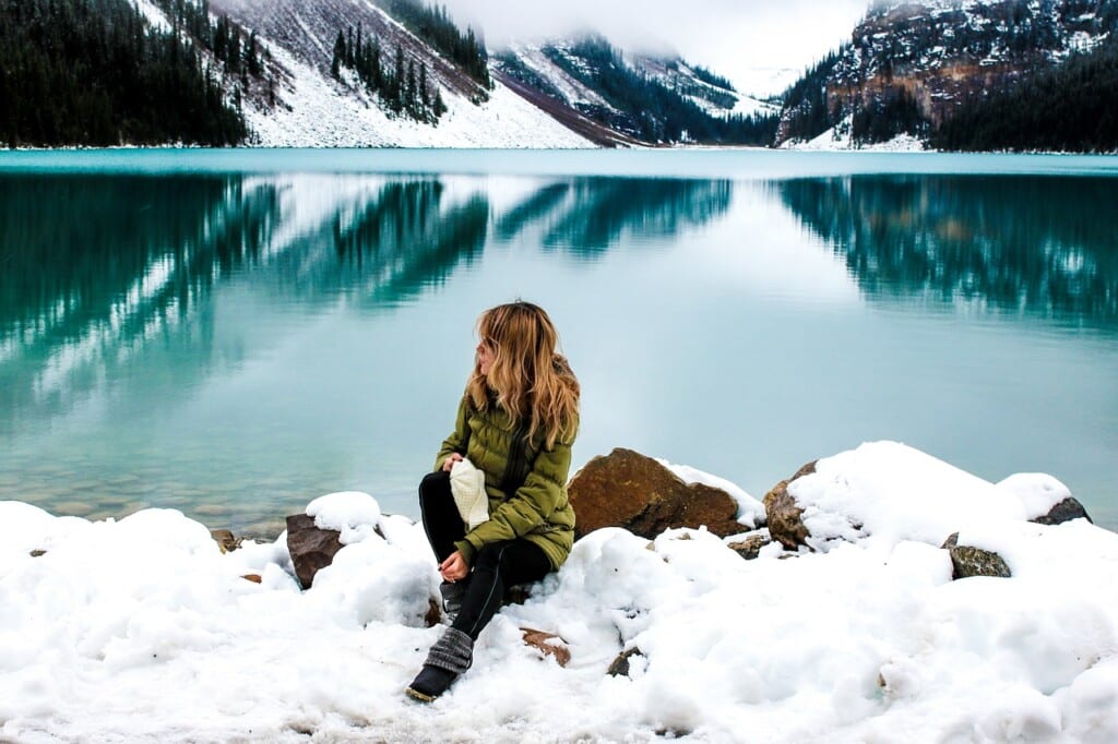 Žena sedící před ledovým jezerem.
