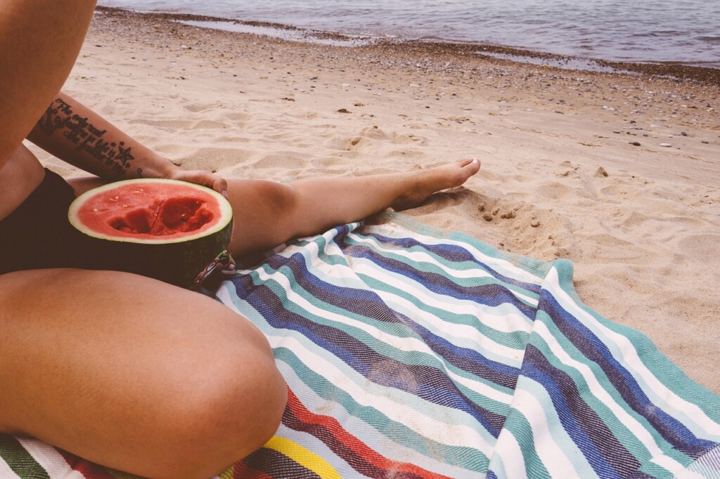 Žena jí meloun na pláži.