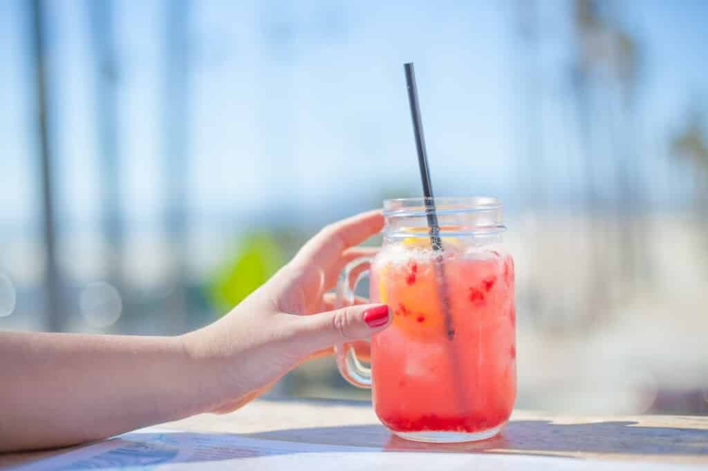 Osvěžující letní drink ve sklenici s rukou.