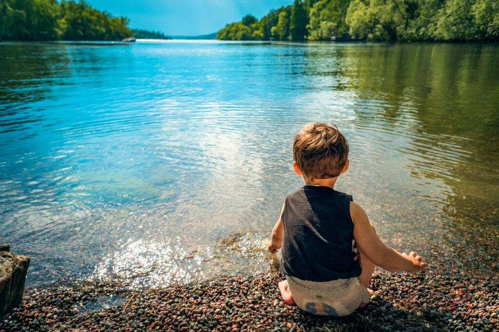 Malý chlapec si hraje na břehu jezera.