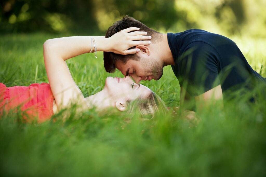 Zamilovaný pár při polibku v trávě.