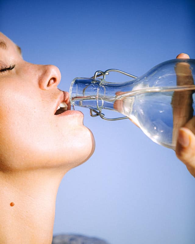 Žena pije z lahve s vodou.