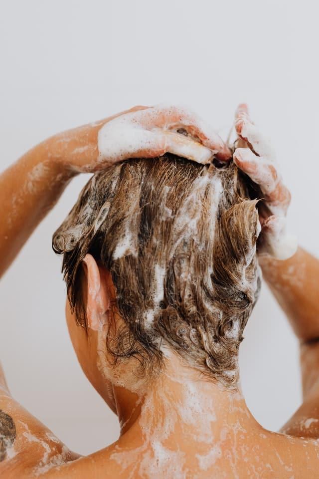 Žena si myje hlavu, aby se zbavila lupů.
