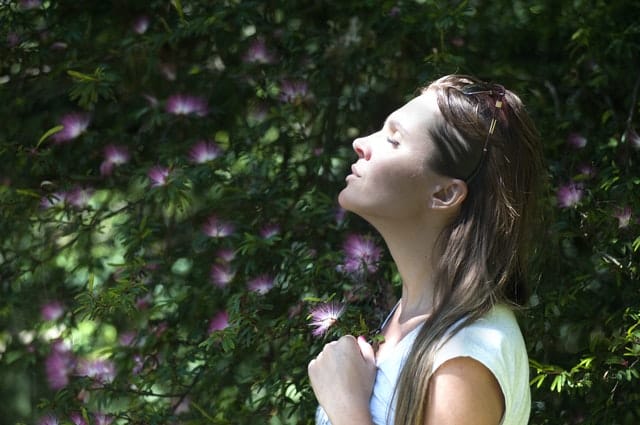 Žena dýchající nosem v přírodě.
