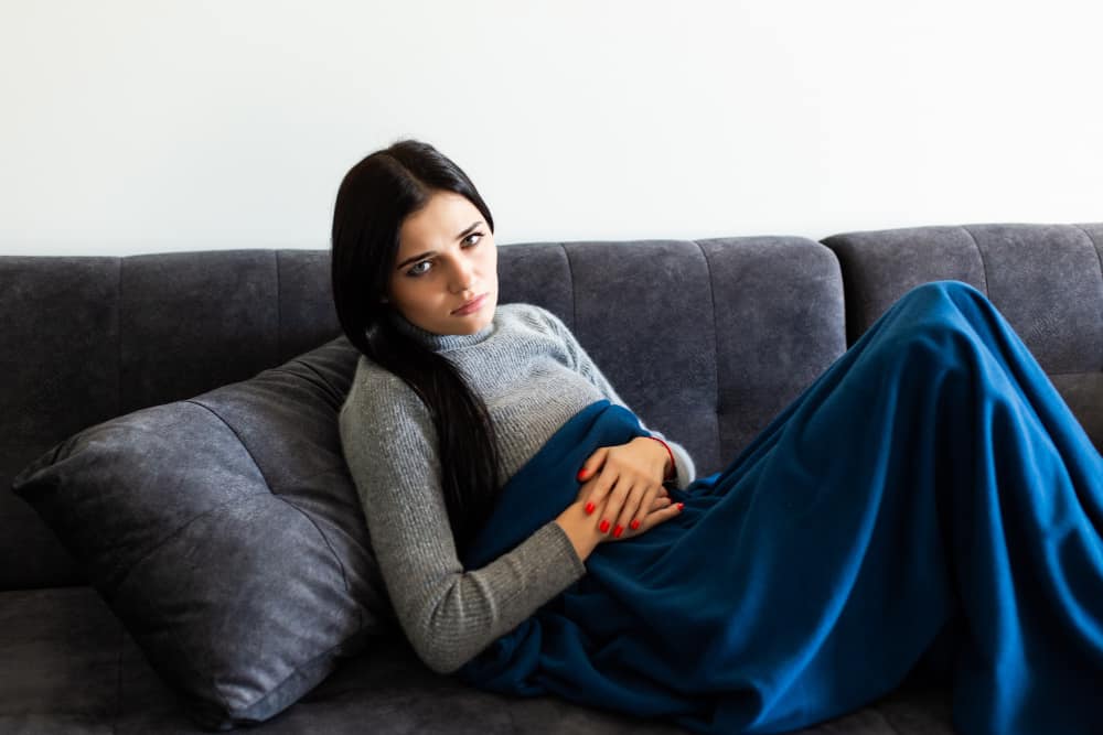 Unavená žena trpící endometriózou na sedačce.