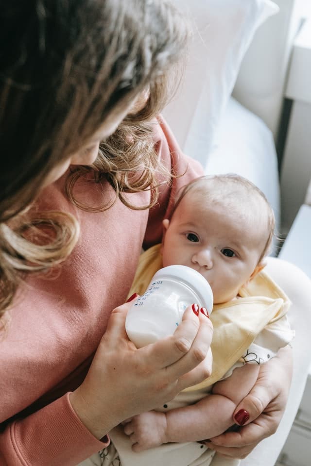 Matka krmí dítě odstříkaným mateřským mlékem.