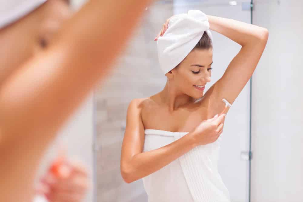 Žena si holí podpaží jako prevenci před zápachem.