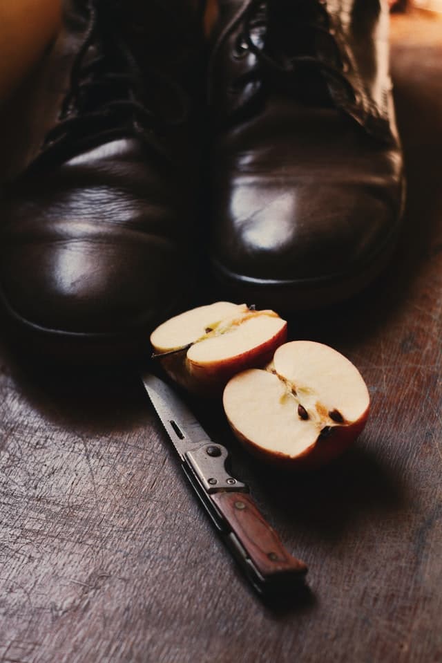 Boty, nůž a rozkrojené jablko se semínky.
