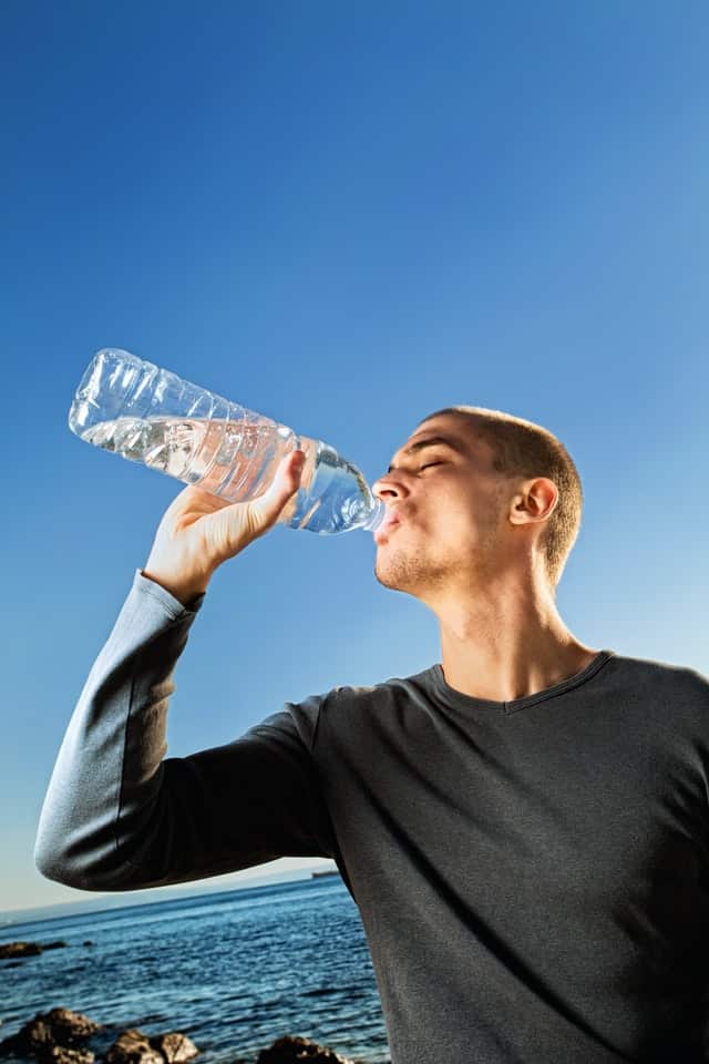 Muž pijící vodu z lahve.