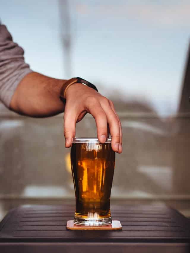 Muž držící sklenici piva v ruce.