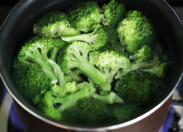 Vařená brokolice v hrnci s vodou.